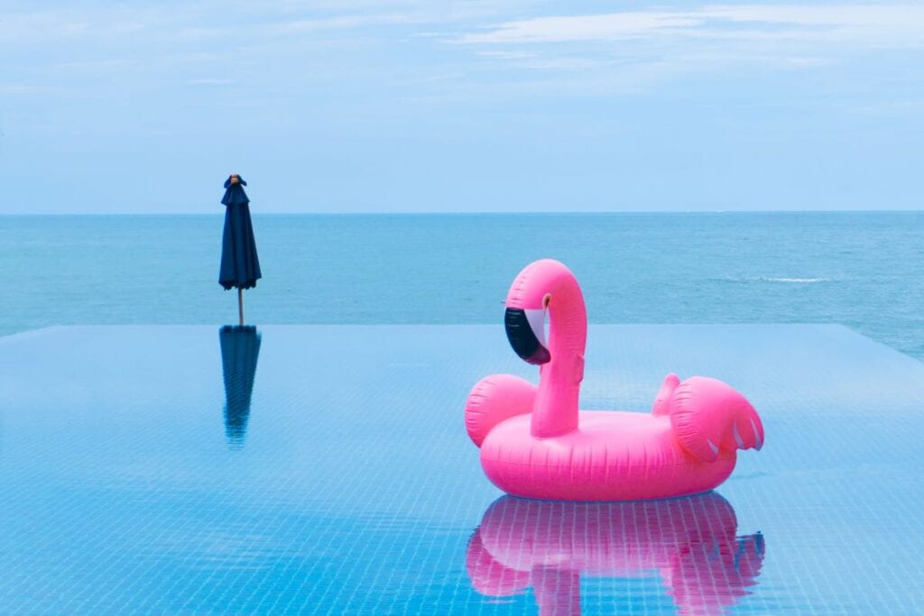 Hot pink flamingo pool float in infinity pool overlooking the sea