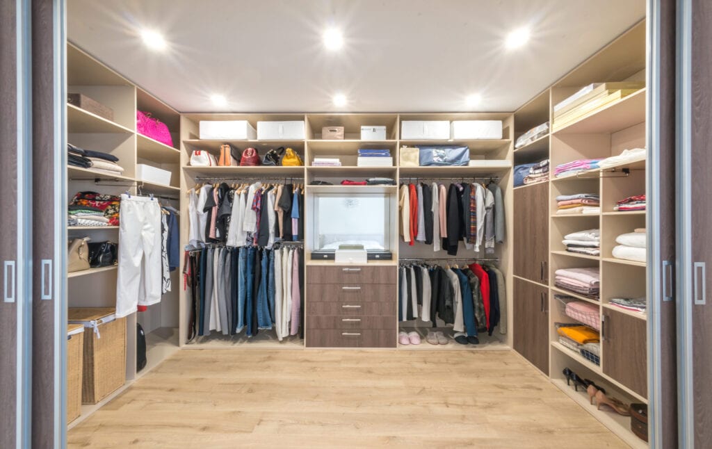 Big wardrobe with different clothes for dressing room. Walk in closet