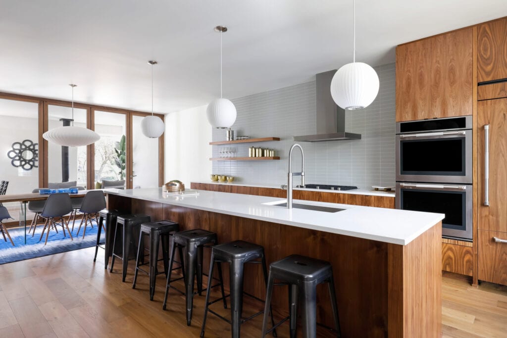 Modern kitchen with black metal barstools and wood island with white countertops