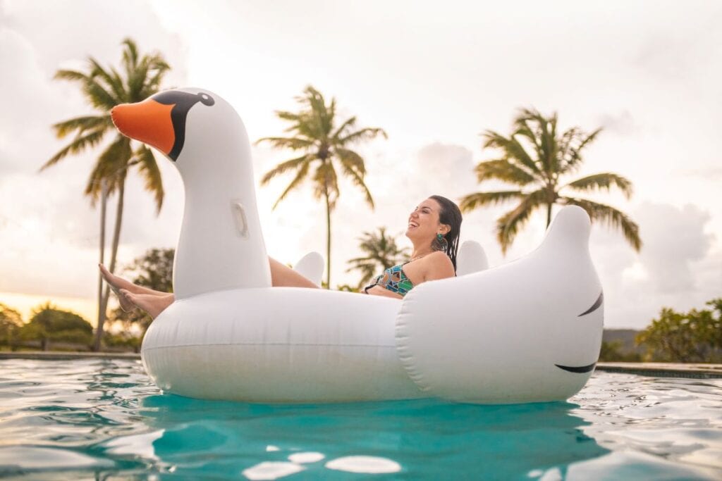 Young woman relaxing in pool on swan-shaped pool float