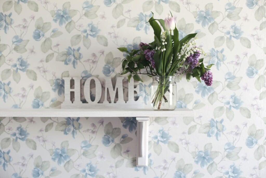 Wall with floral wallpaper and shelf with decor