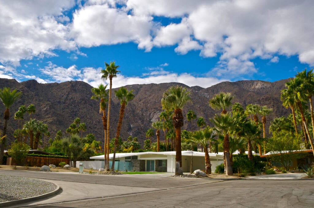 "The San Jacinto Mountains are seen in this scenic view in Palm Springs, California. The city is famous for it's many Mid-Century Modern architectural style homes such as the ones in the foreground. California Fan Palm Trees are seen throughout the area, planted when the homes were built. Coachella Valley, Riverside County, Southern California, Western USA.