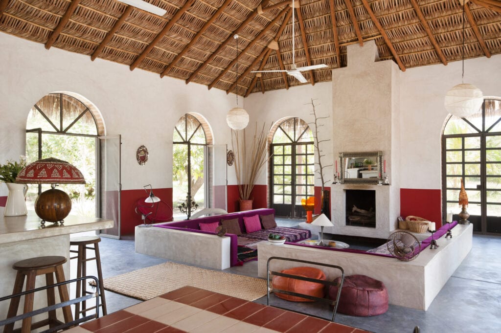 Open plan sitting room with polished concrete floor, iron framed french windows and a "Palapa" roof made from woven palm leaves