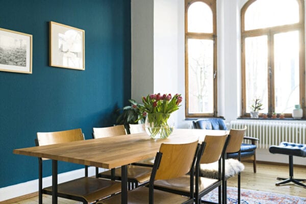 Wooden table and chairs with large window front in modern living room in stylish apartment