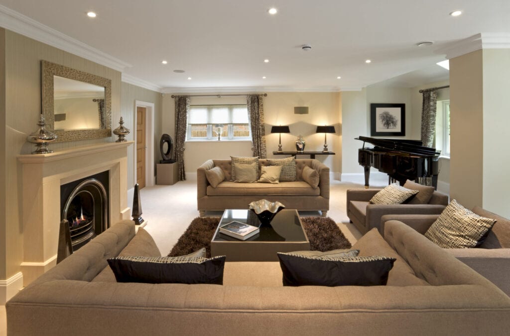 Luxurious living room in an expensive new home that has been decorated and furnished by a leading Interior Designer. The room comprises two large double seat and two single seat settees, a beautiful lit fireplace, a grand piano and lots of elegant silk cushions.