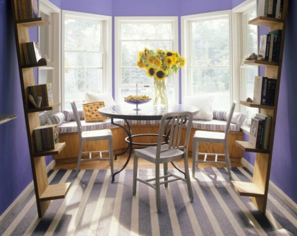 Small dining room with bay window and leaning bookshelves