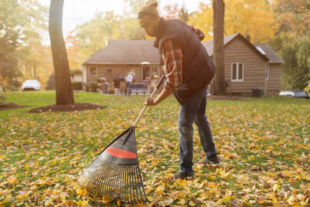 man raking leaves in his backyard