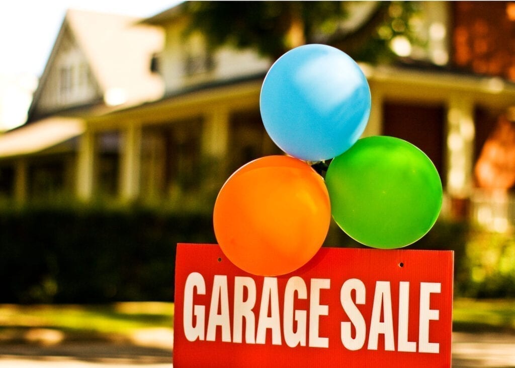 Red garage sale sign with balloons in front of house