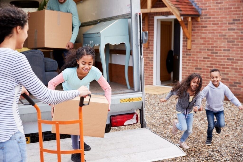 Family packing moving truck during fall with leaves on the ground