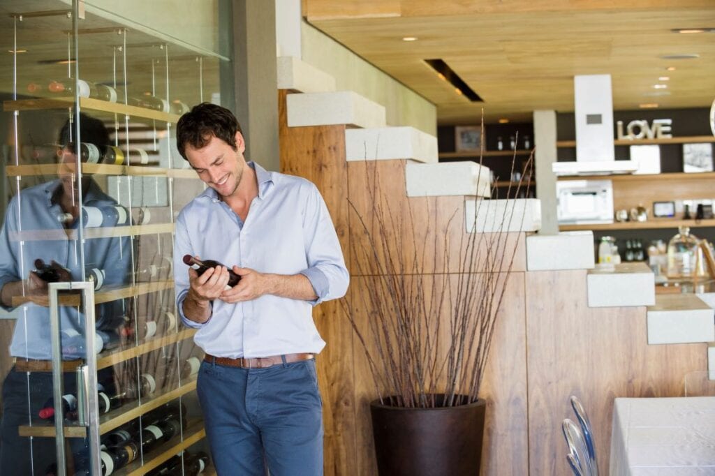 Man looks at wine from beautiful wine case in contemporary home