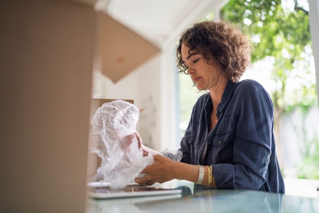 Woman wrapping objects in bubble wrap to prepare for moving