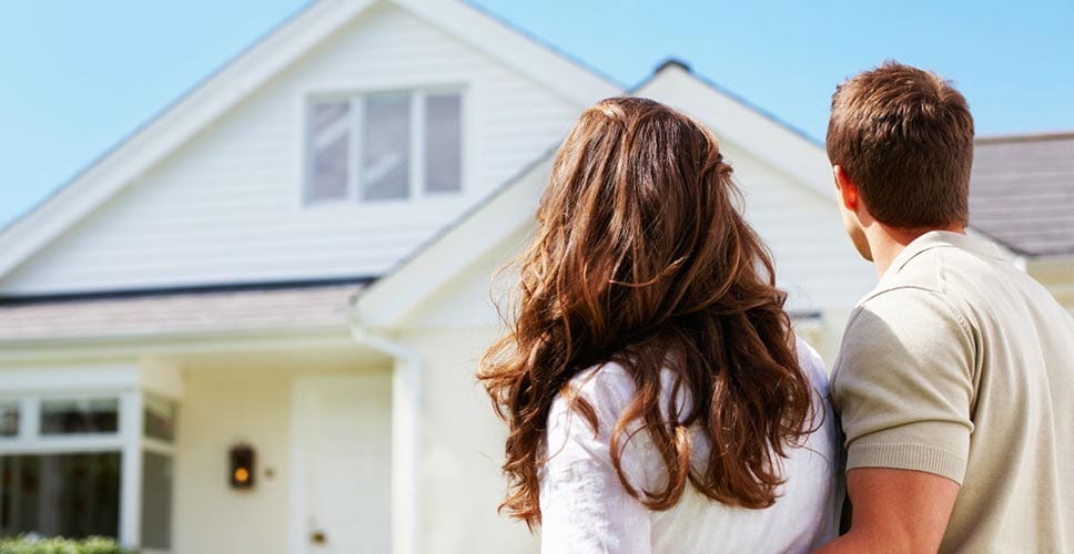 Young couple stands in front of their next home.