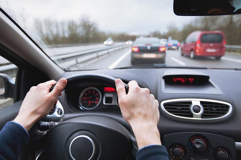 Hands on steering wheel in car in traffic