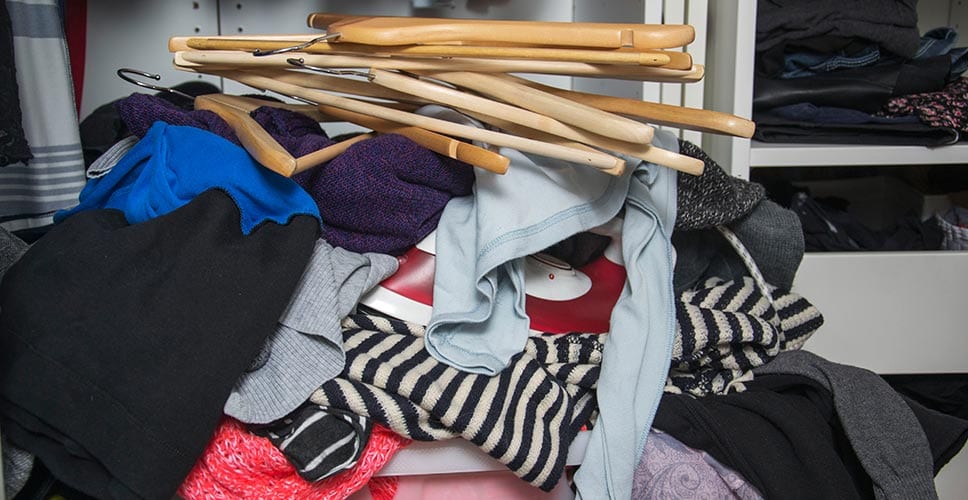 Pile of clothes stacked on a closet floor.