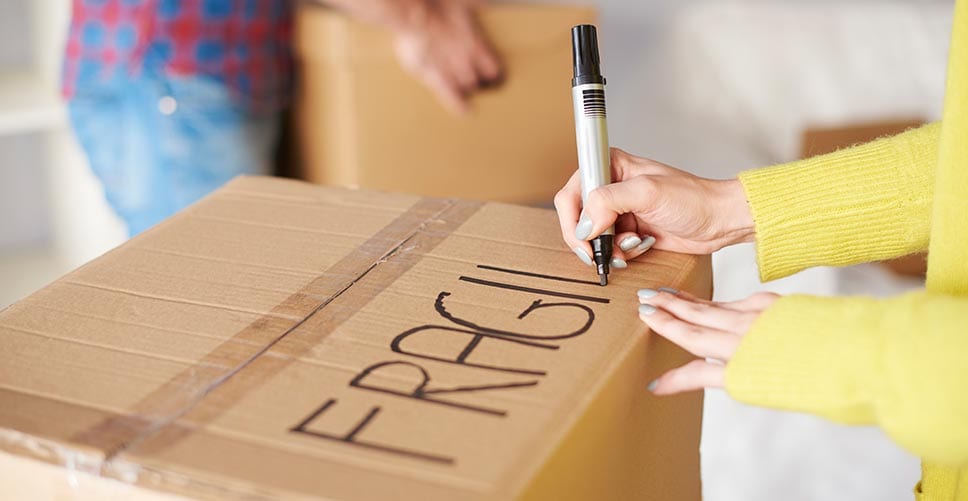 A woman properly labeling her boxes so she doesn't make a common packing mistake.