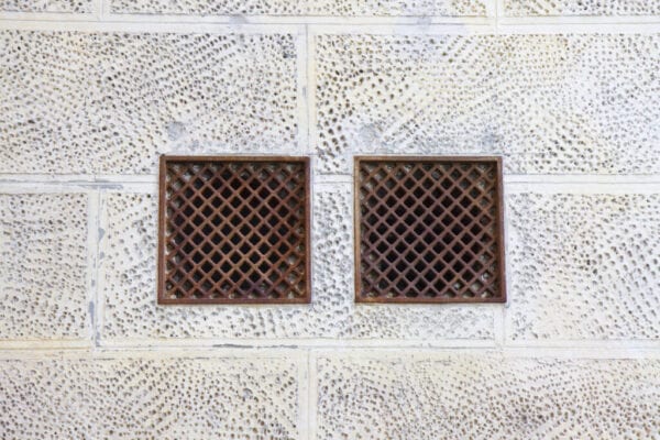 Cast iron ventilation grilles against a plaster wall