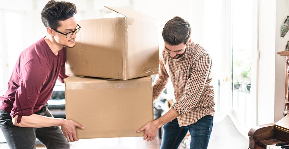 Two professional movers help bring in boxes to a new house.