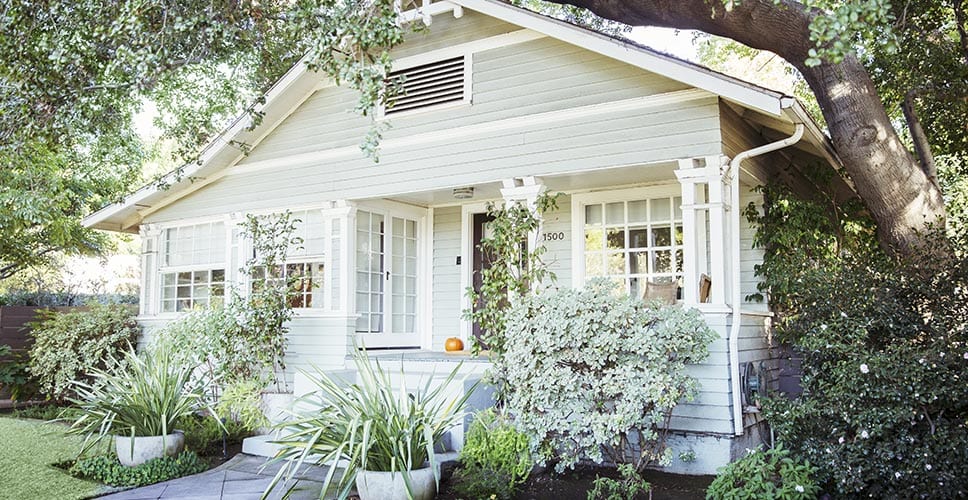 A cute historic home surrounded by lush greenery.