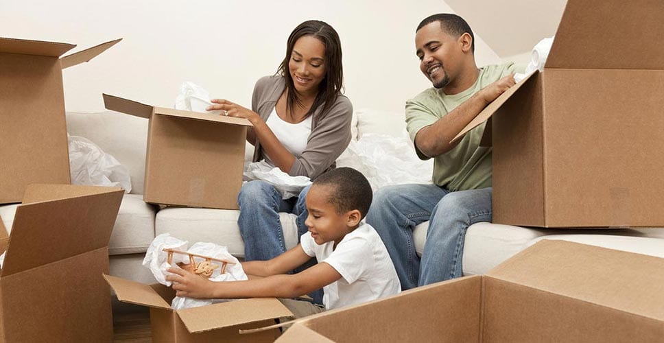 Young family packs boxes with their infant child and prepare for a big move.