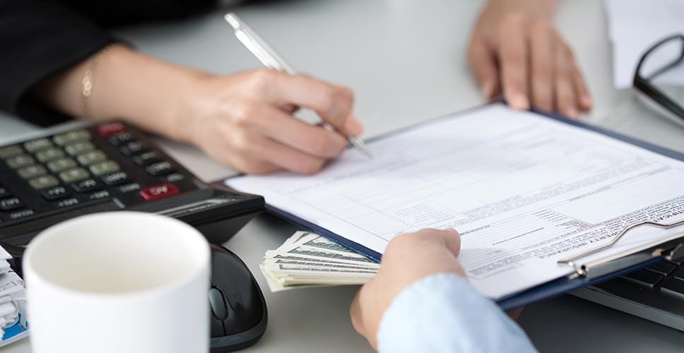 Woman signs a contract and hands over money for her new rental. She took care not to fall for common rental scams.