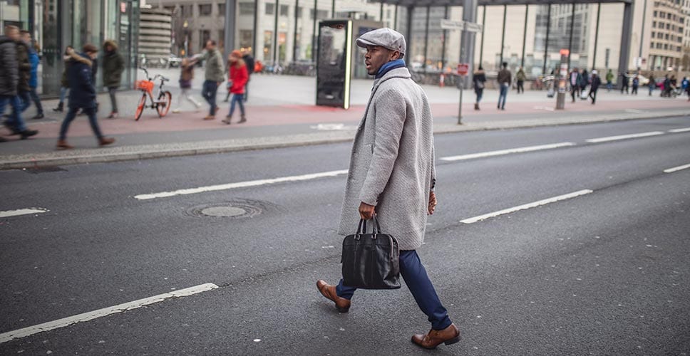 man walking across the street in a city