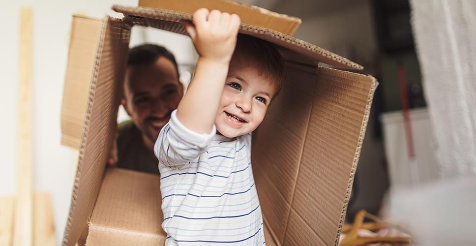 toddler playing in an empty box shows that moving with an infant can be challenging