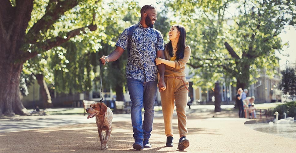 young couple walking in a park with their dog in their new neighborhood