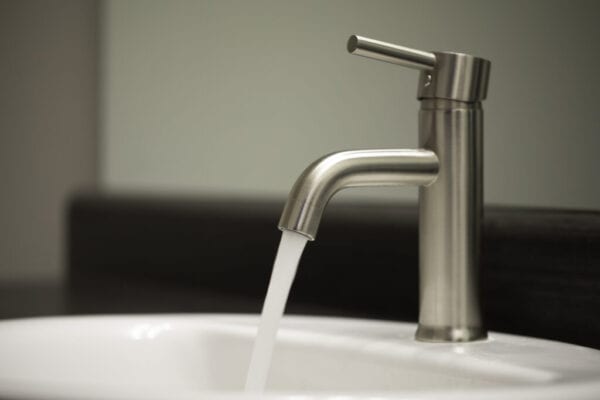 Metal bathroom sink faucet shot close up with running water