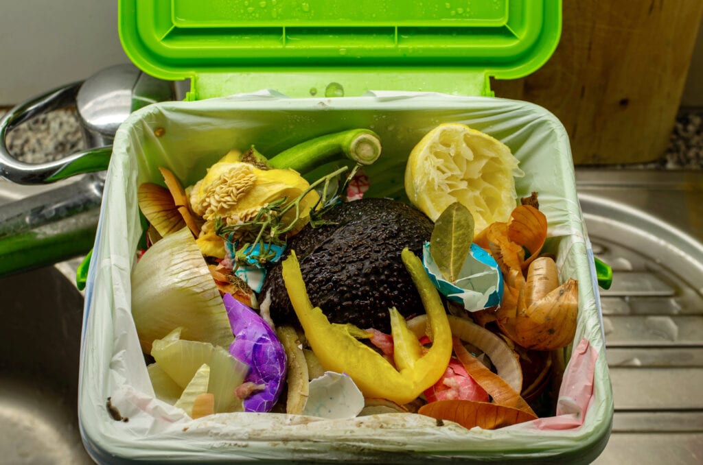 Home food waste container full leftovers vegetables in a plastic bag close up shot in the kitchen 2020