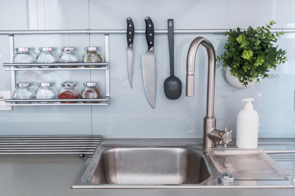 Kitchen sink surrounded by other kitchen utensils and objects