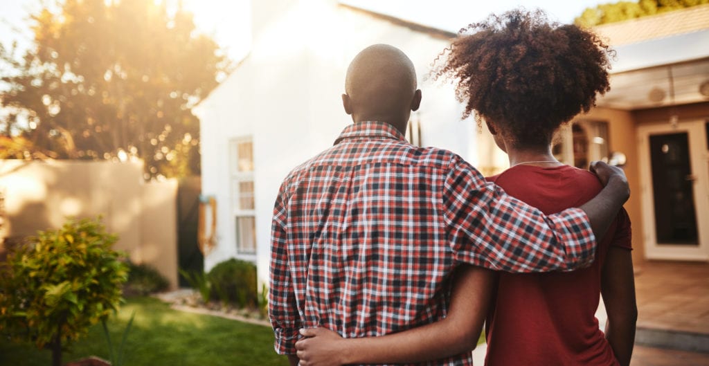 Rear view shot of a young couple admiring their new house.