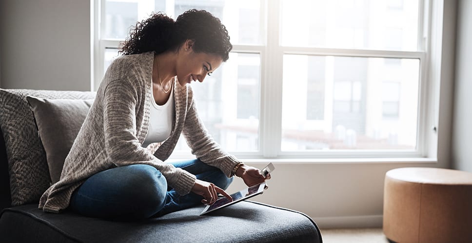 Young woman using tablet to access internet service in her new apartment.