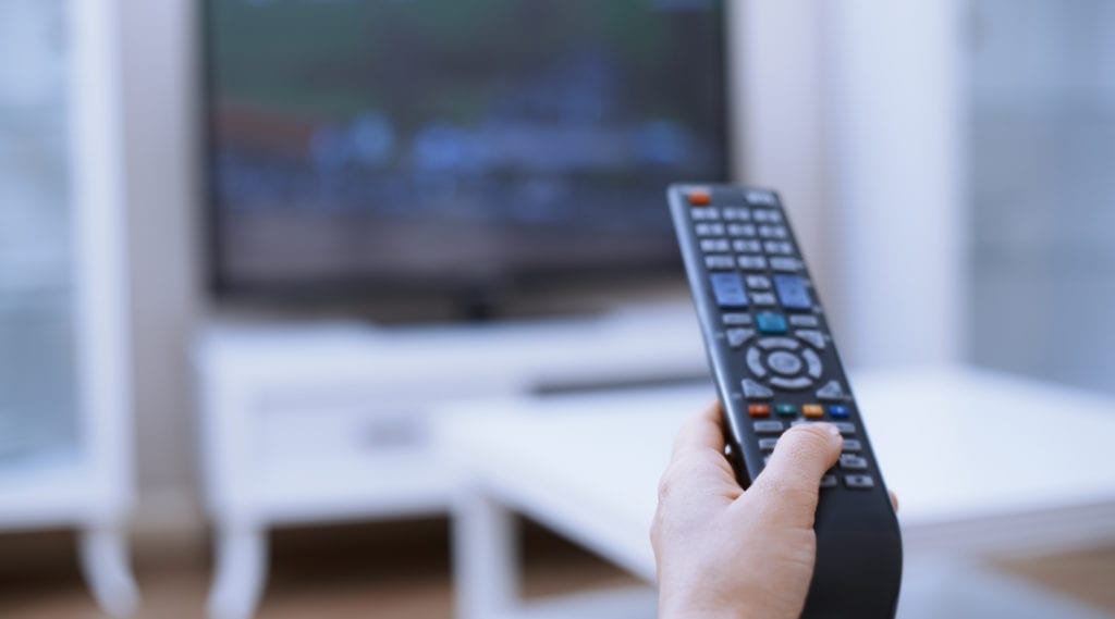 A new homeowner uses the remote to turn on programming provided by his new TV service provider.