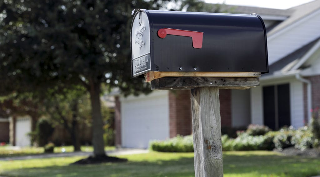 A mail black mail box in front of a new home.