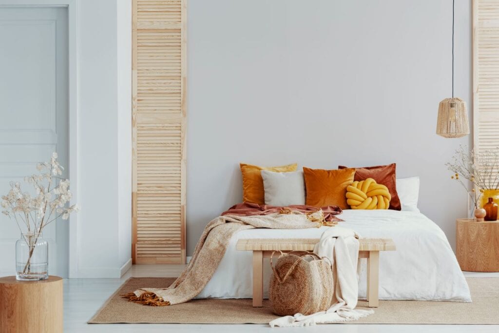 Small bedroom with white comforter and colorful orange accents