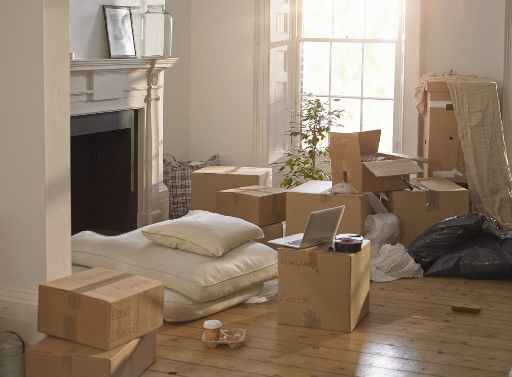 A room full of packing boxes and junk and a laptop