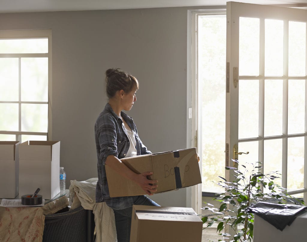 A woman carrying moving boxes at home