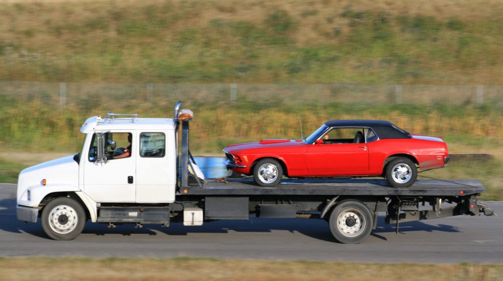 White truck towing red car
