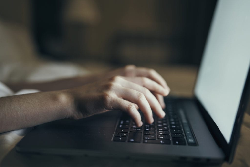 Hands typing on laptop