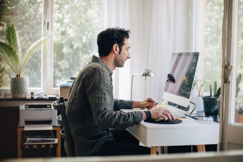 man uses desktop computer in home office