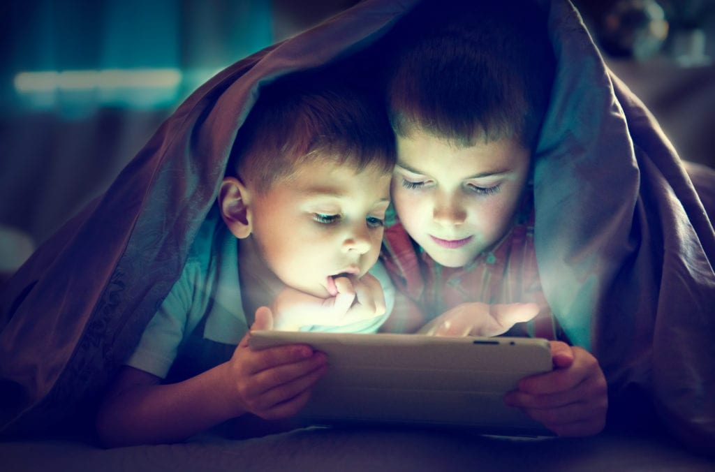 Kids using tablet under a blanket