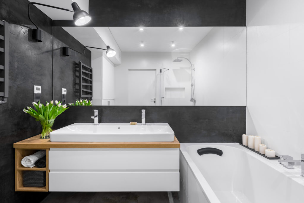 Modern bathroom interior with black wall and wide mirror