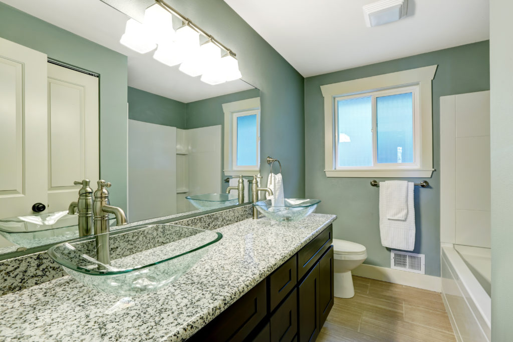 Cerulean bathroom with granite counter and wide mirror