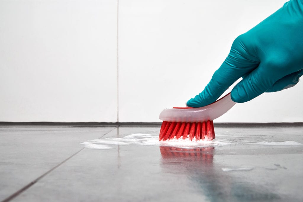 Scrubbing floor with toothbrush and glove