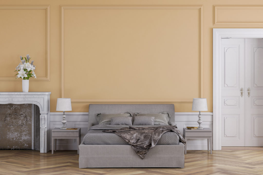 Empty glamour bedroom with decoration on hardwood floor in front of empty apricot orange antique wall with copy space, a fireplace on the left and a door on the right. Slight vintage effect added