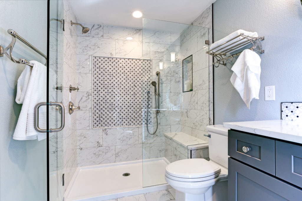 Bathroom with blue cabinets and marble shower tiles