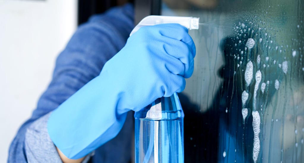 Man cleans window with vinegar and water in a spray bottle.