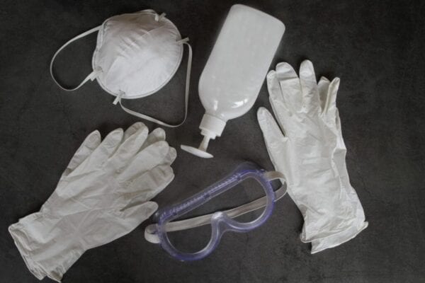 Face mask, , liquid soap, protective gloves and protective eyeglasses on black background