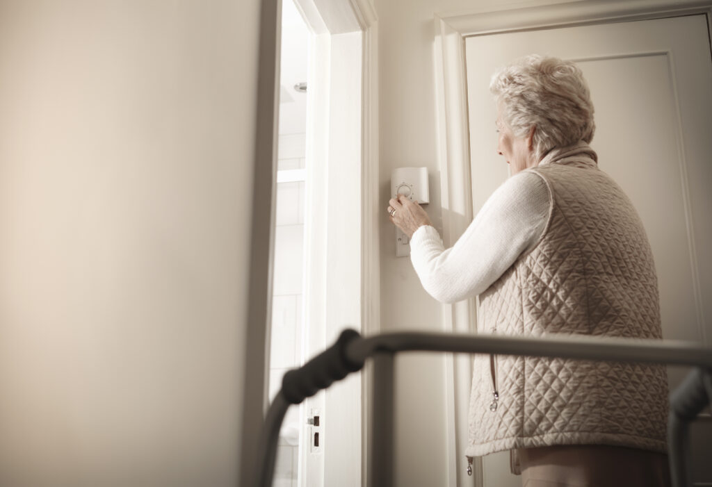 Senior woman adjusting thermostat in hallway