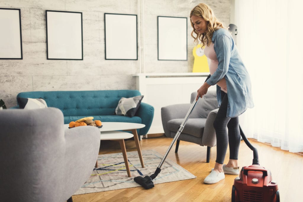 A pregnant woman cleans her carpet with homemade carpet shampoo